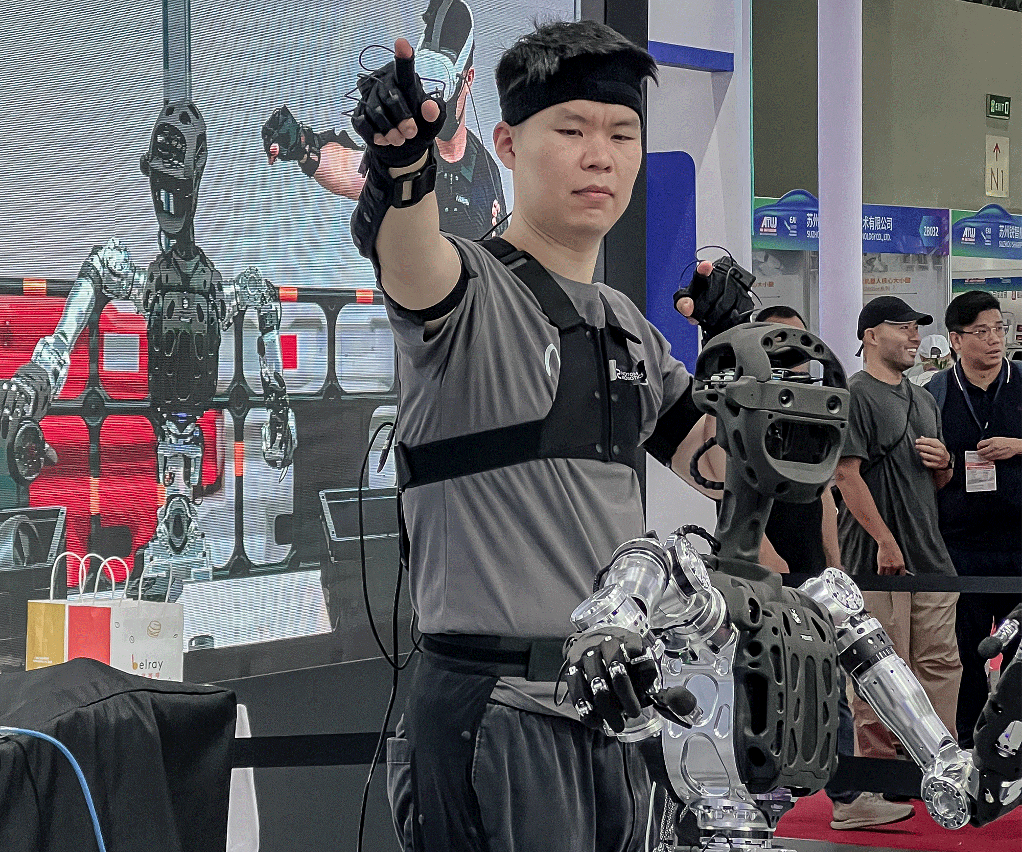 Teleoperating-Adam-U-Humanoid-Robot-with-Motion-Capture-at-WAIC-2025 Operator using a motion-capture suit to teleoperate the Adam-U humanoid robot at the World Artificial Intelligence Conference 2025, demonstrating real-time embodied AI data collection with synchronized movement and tactile sensing.